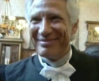 Dominique de Villepin en robe d'avocat, dans la salle d'audience de la première chambre de la cour d'appel. Il porte sous la robe ce qui semble être un maillot de type T-shirt, et a donc le nœud papillon blanc des prestations de serment attaché autour du cou.