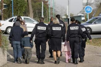 Un groupe de policier escorte une famille avec trois enfants après une audience de reconduite à la frontière au tribunal administratif de Cergy Pontoise. Photo :  AFP/Jack Guez