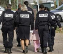 Six policiers entourent et escortent une fillette d'environ quatre ans, tache de rose au milieu du bleu nuit.